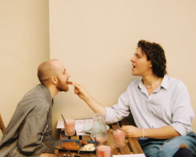 Feeding a friend a piece of cake across a café table, July 2025